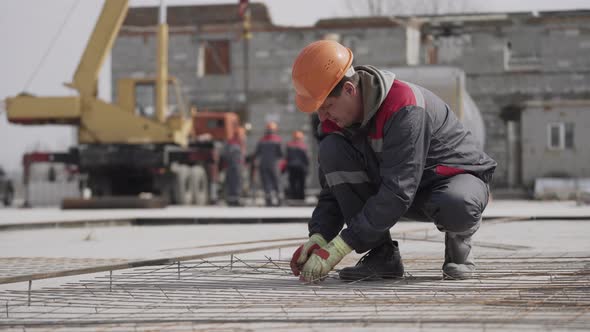 A Man in a Helmet Making Steel Mesh Before Put Concrete