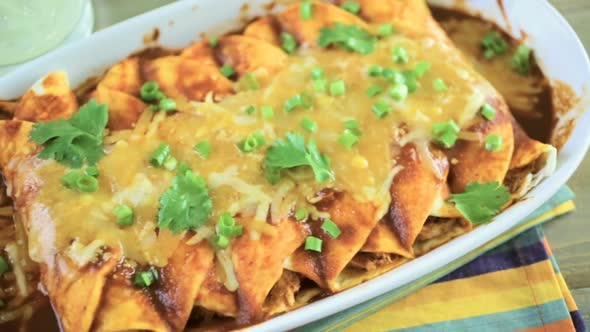 Homemade chicken enchiladas garnished with green onions and cilantro in a white casserole dish.