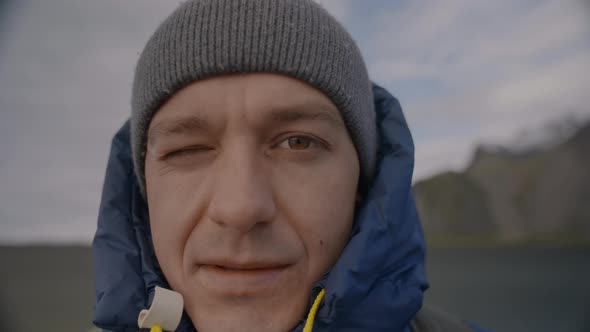 Man Looking At Camera With One Eye Open On Beach