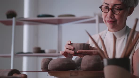 Asian elderly woman enjoying pottery work at home.