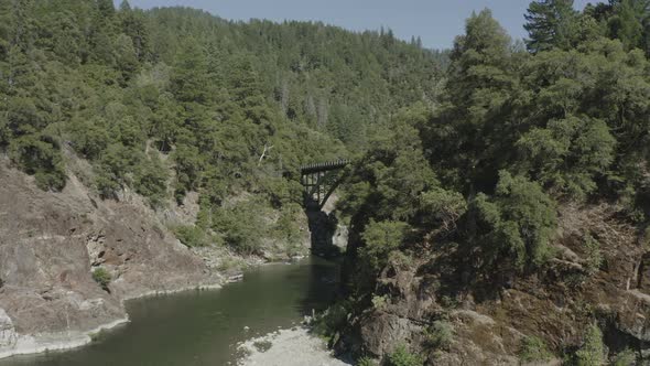 Slow panning drone flies to reveal a tall bridge over a river in a steep canyon