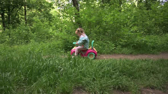 Child Riding a Toy Car in the Forest Park