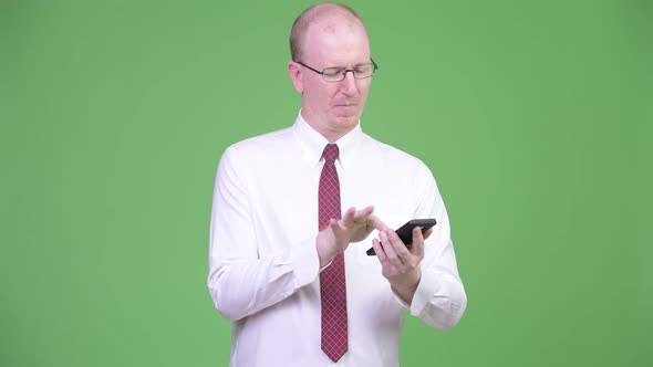 Happy Mature Bald Businessman Using Phone