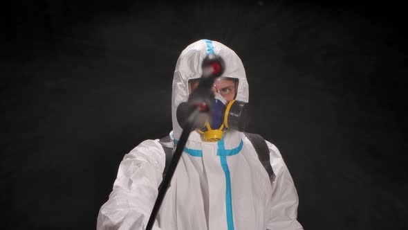 Man Wearing Personal Protective Suit, Safety Glasses, a Respirator and Gloves for Disinfection and