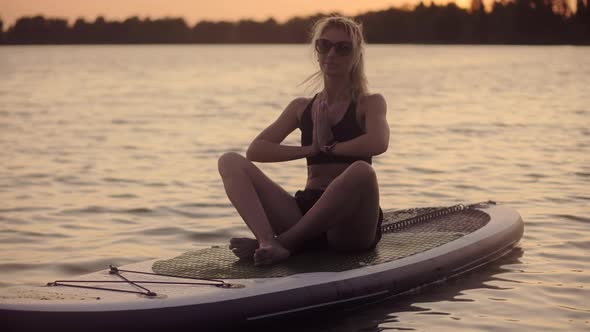 Lotus Position Yoga On Sup Board At Sunset. Mental Health Outdoor Summer Activity.