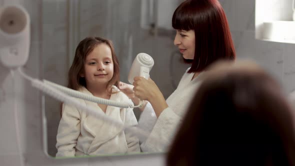 Mother is Brushing and Drying Child Hair After Shower Girl is Looking at Mirror