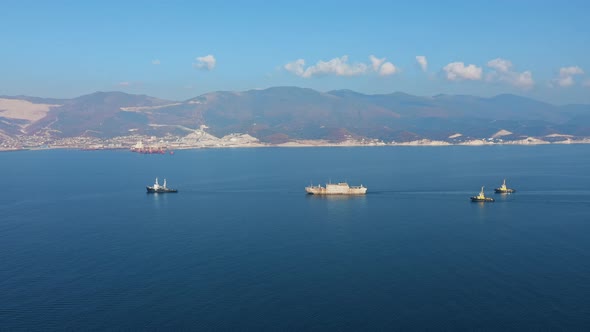 Aerial View of Large Cargo Ship Leaving Sea Port at Sunny Day