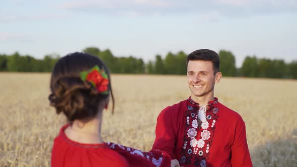 Young woman holding male hand, walking and running on endless wheat field. Slow