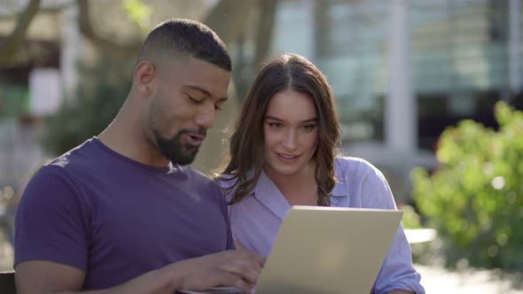 Man Showing Woman Something on Laptop, Both Looking Involved 