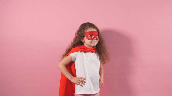 Attractive Cute Kid Wearing Red Superhero Suit and Mask Standing Showing in Side Isolated Over Pink