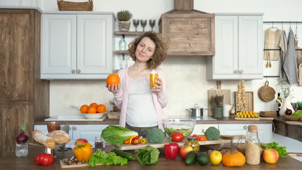 Pregnancy And Healthy Diet Concept. Pregnant Woman With Orange Juice On Kitchen.