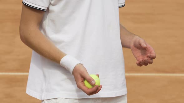 Man wearing white t-shirt throwing yellow tennis ball, training at stadium