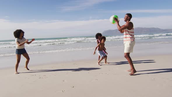 African american parents and their children playing with a ball on the beach