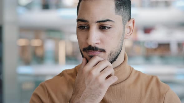 Young Perplexed Worried Arab Man with Serious Expression Thoughtfully Keeps Hand on Chin Thinking