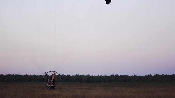 The Motor Paraglider Lowers the Parachute After Landing and Stops Completely in the Field After