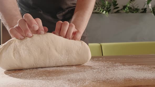 Man Baker Kneads Dough for Baking and Bread on Wooden Table