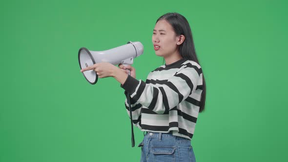 Side View Of Asian Woman Speaking On Megaphone In The Green Screen Studio