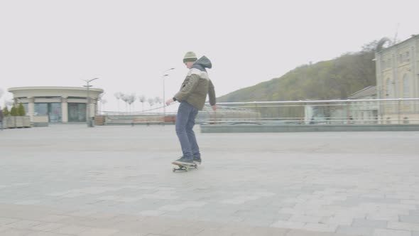 Teen Skater Practicing Shuvit Trick in City Square