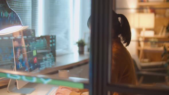 Asian Woman Working with Financial Data in Office at Night