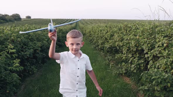 Schoolboy Playing with a Plane Toy in the Summer Field