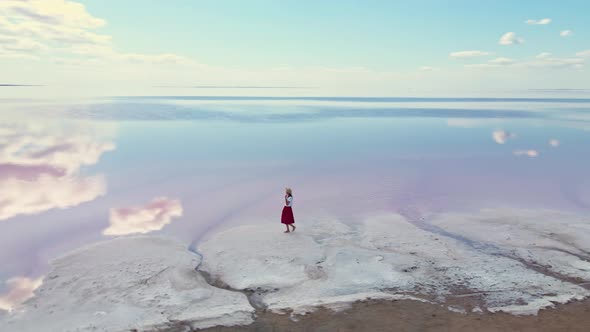 Happy Carefree Woman in Red Skirt Walks Salty Lake Shore with Clouds Reflections