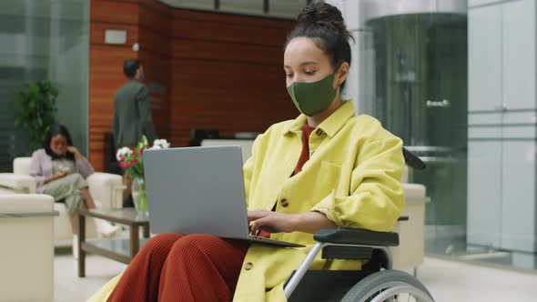 Masked Businesswoman Working on Laptop in Wheelchair