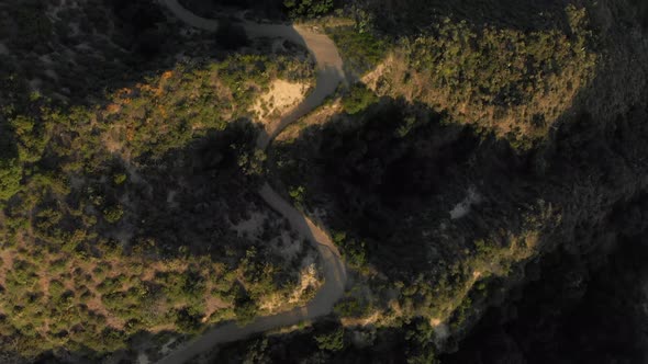 Aerial Pan and Tilt Down from a Winding Road to a Verdant Mountain