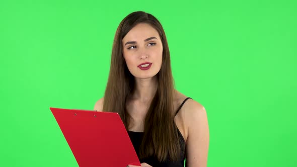 Woman Fills Papers in Red Folder with Pen. Green Screen