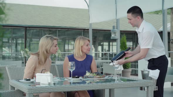 Professional Male Waiter Showing Clients Wine and Opening Bottle. Portrait of Caucasian Man Serving