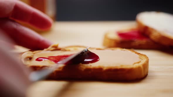 Close Up of Hands Spreading Cherry Jam on Toast While Having Breakfast
