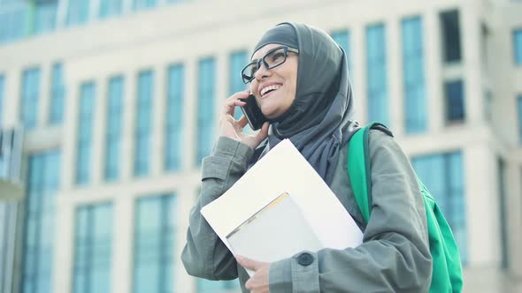 Cheerful Arabic Female Student Talking on Phone Standing on University Campus