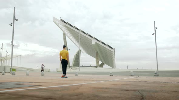 Young Attractive Trendy Man skateboarding fast under a solar panel on a morning sunny day with an ur