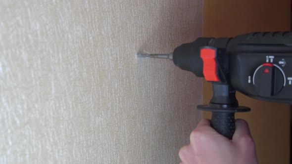 Male Hands Drill a Hole in the Wall with a Wallpaper Drill