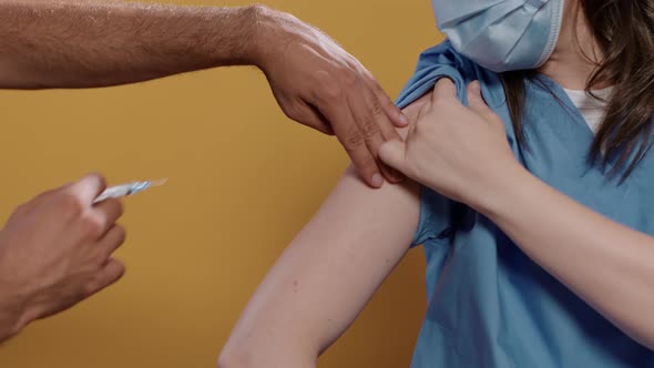 Closeup of Medical Doctor Wearing Surgical Mask Lifting Sleeve and Recieving Covid or Flu Vaccine