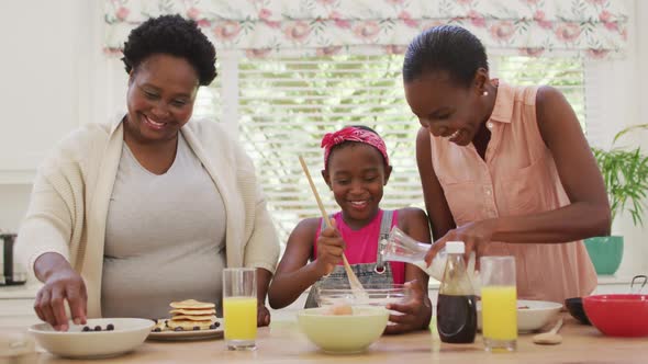 African american grandmother, mother and daughter preparing dinner in the kitchen at home