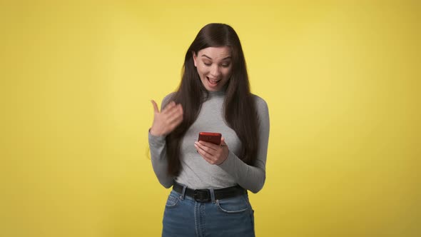 Slender Woman in Gray Turtleneck or Sweater Holds Red Phone in Her Hands and Wins Match or Bet