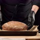 man chef in black uniforms and black latex gloves holds round baked bread  - VideoHive Item for Sale