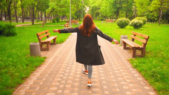 Happy Woman with Red Hair Walks in the Park