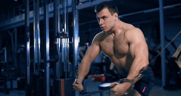 Bodybuilder Doing Exercise on the Simulator in the Gym