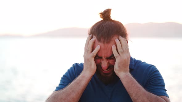 Bearded man with headache giving his hands to the head