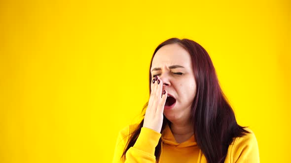 Close Up of Young Woman Yawning From Fatigue on Yellow Background