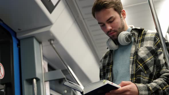 Handheld Young Guy Rides the Subway and Reads a Book a Student Goes to Study at the University