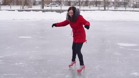 Young Woman in Winter Clothes and Highheeled Shoes Glides on Ice