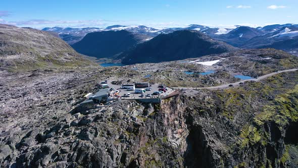 Fly away from a Viewpoint on the edge of a cliff surrounded by mountains