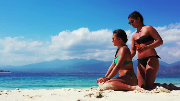 Women best friends on idyllic island beach journey by blue green lagoon with bright sand background 