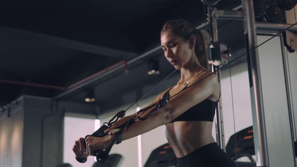 Sporty woman exercising on multistation at gym for arm and shoulders muscles. Fitness Gym