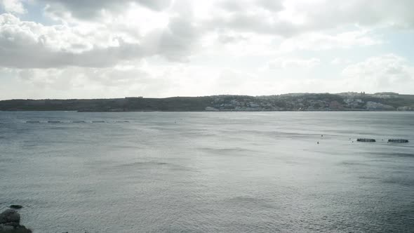 AERIAL: Gloomy and Cloudy Day in Mellieha Bay with Fish Farm Cages Placed in Water