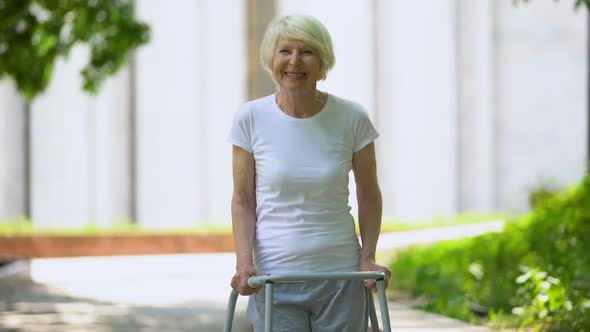 Cheerful Senior Woman With Walking Frame Looking at Camera Outdoors, Rehab