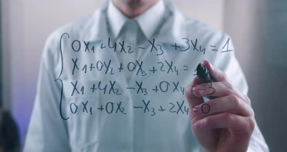 Male Scientist Thinks Over the Solution of the Equation Drawn on a Glass Board in a Laboratory