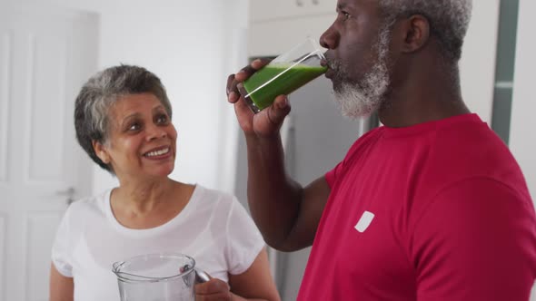 Senior african american man and woman drinking fruit and vegetable health drinks at home